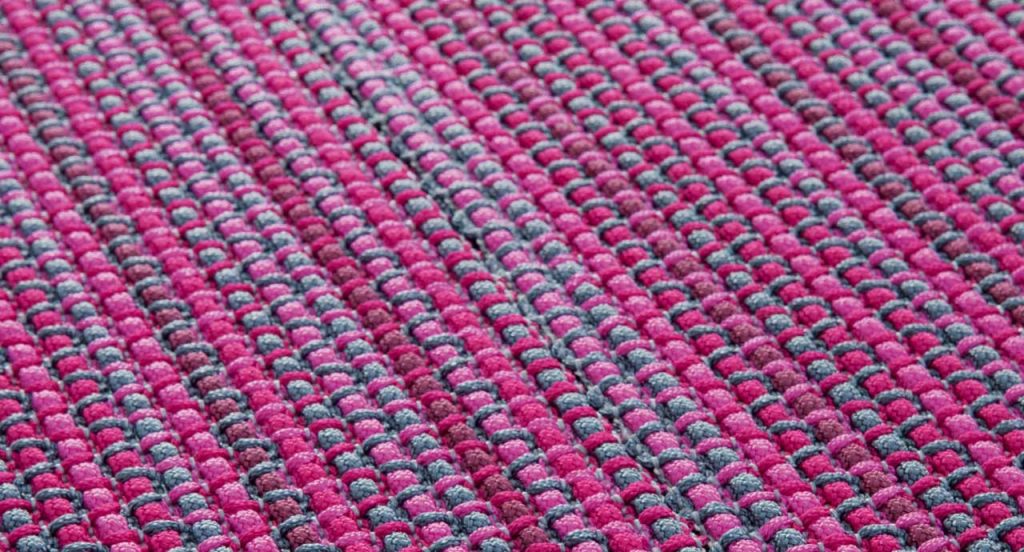 Echo rug made of grey and pink woven strips.