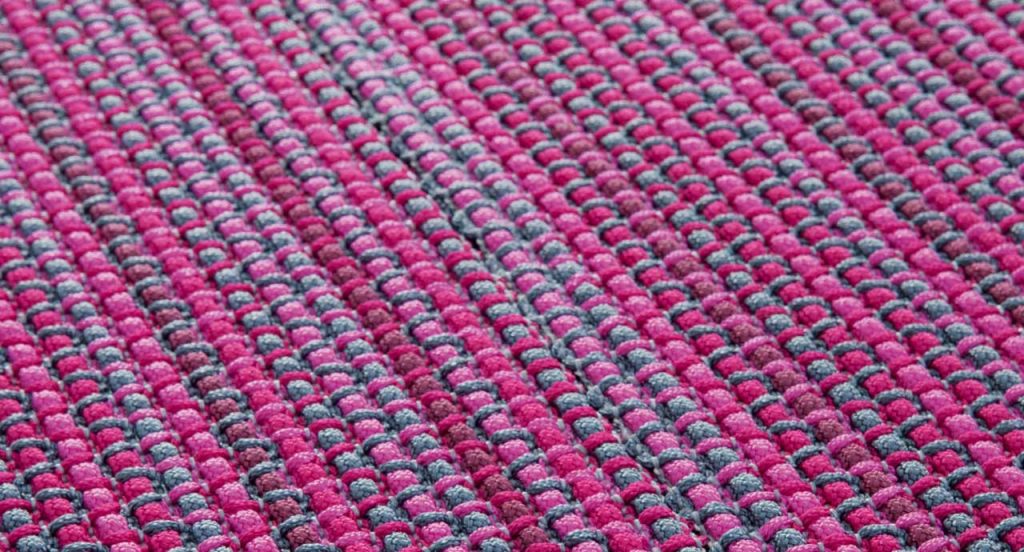 Echo rug made of grey and pink woven strips.