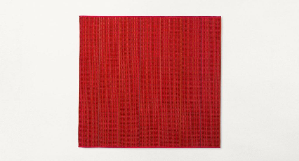 Echo rug made of red woven strips on a white background.