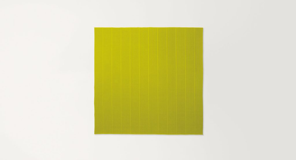 Echo rug made of yellow woven strips on a white background.