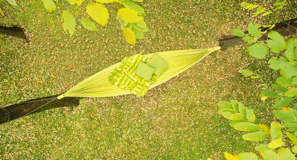 Farniente hammock made of green fabric in a garden.