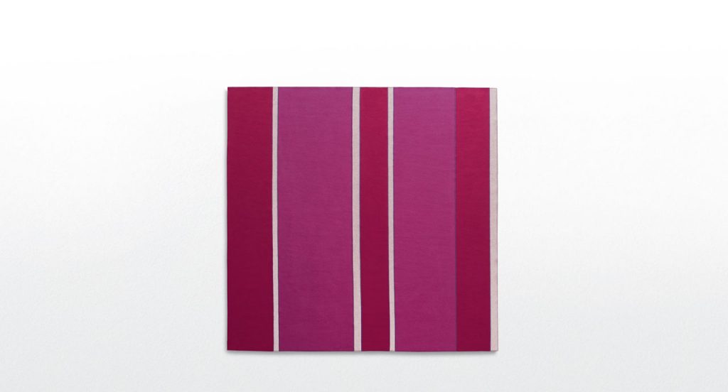 Fashion rug made of pink, red and white felt strips on a white background.