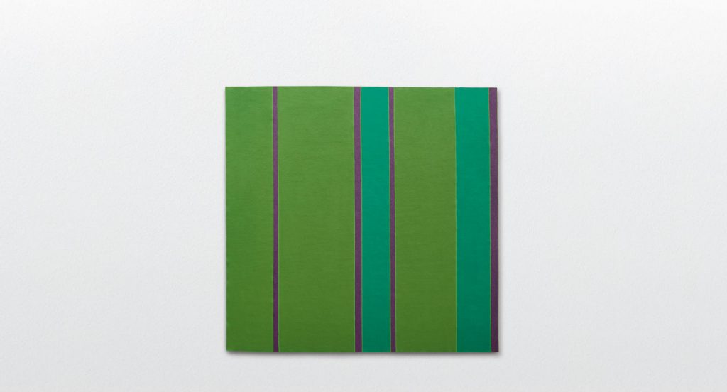 Fashion rug made of green, blue and purple felt strips on a white background.