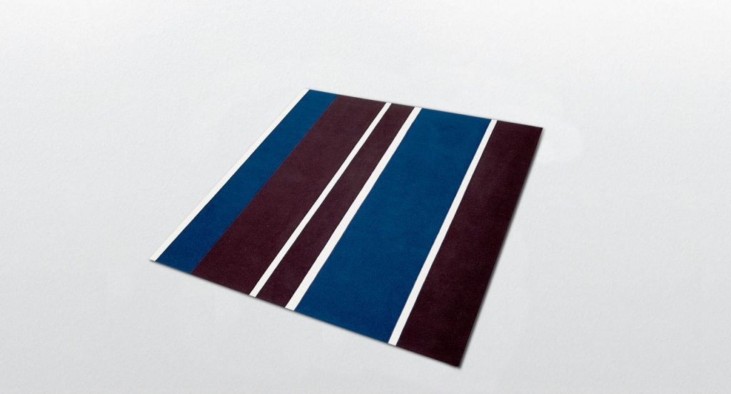 Fashion rug made of brown, blue and white felt strips on a white background.
