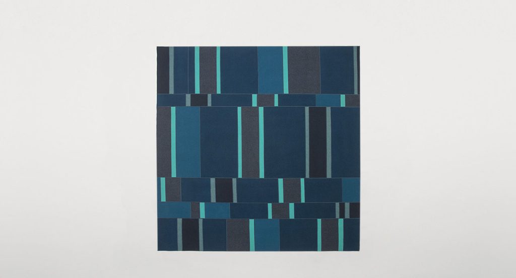 Fashion rug made of brown, blue and grey felt strips on a white background.
