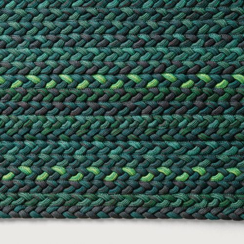 Flutti rug made of green and black braids of wool cords on a white background.
