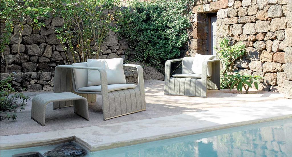 Two Frame Armchairs, upholstery in beige rope braids and two white cushions next to a pool.