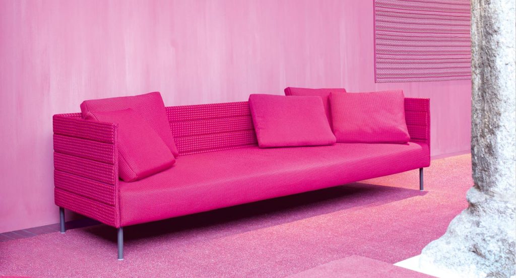 Frame on sofa, legs in black steel, upholstery in pink rope braids, pink seat cushion in a living room.