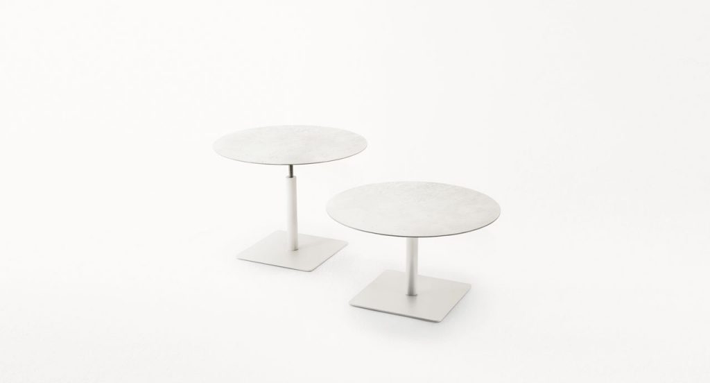 Two white Giro Outdoor Table tables, structure and central leg in steel, top in concrete on a white background.