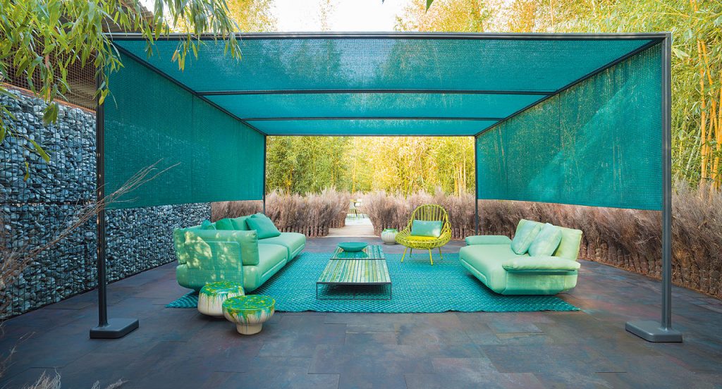 Green Giunco armchair, structre and four chairs in steel, two cushions in fabrics in a terrace.