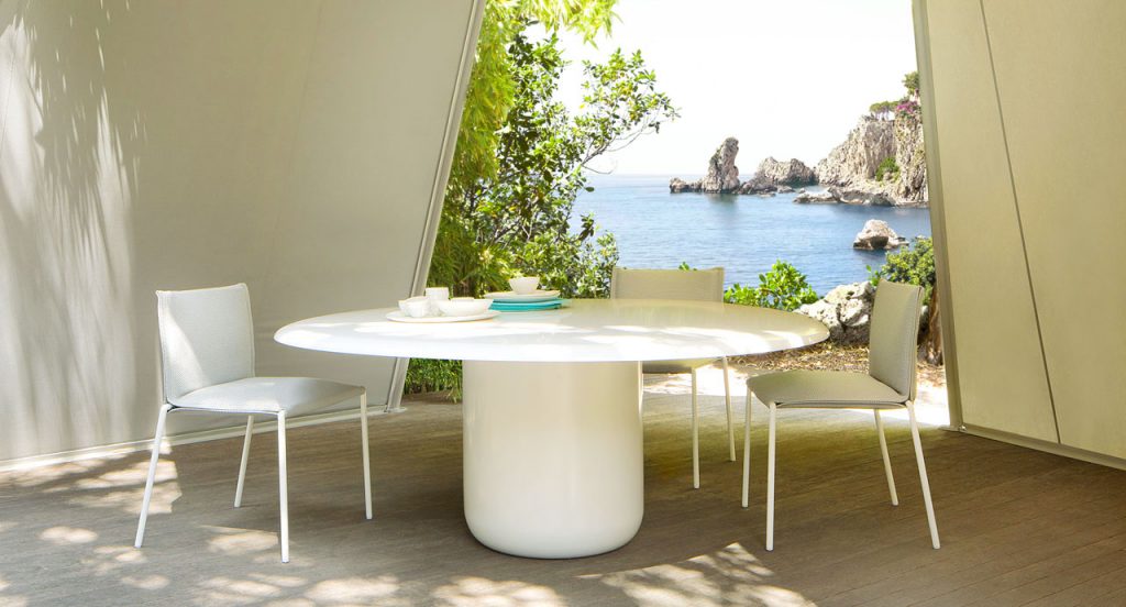 Gon Round Table, top and central leg in white steel with two chairs in a terrace.