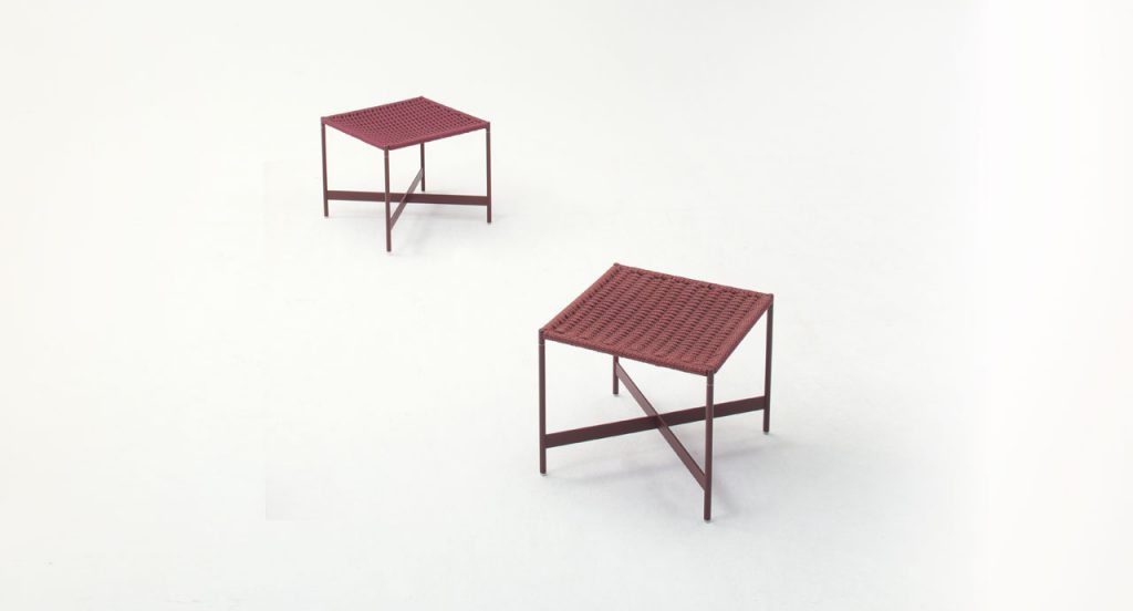 Two red Heron Stools, structure and four legs in steel, upholstery in rope cord on a white background.