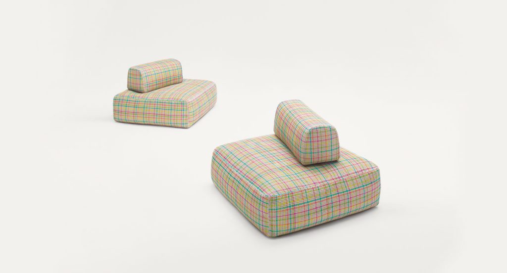 Two Hopi poufs, upholstery in blue, pink, orange and yellow lines pattern on a white background.