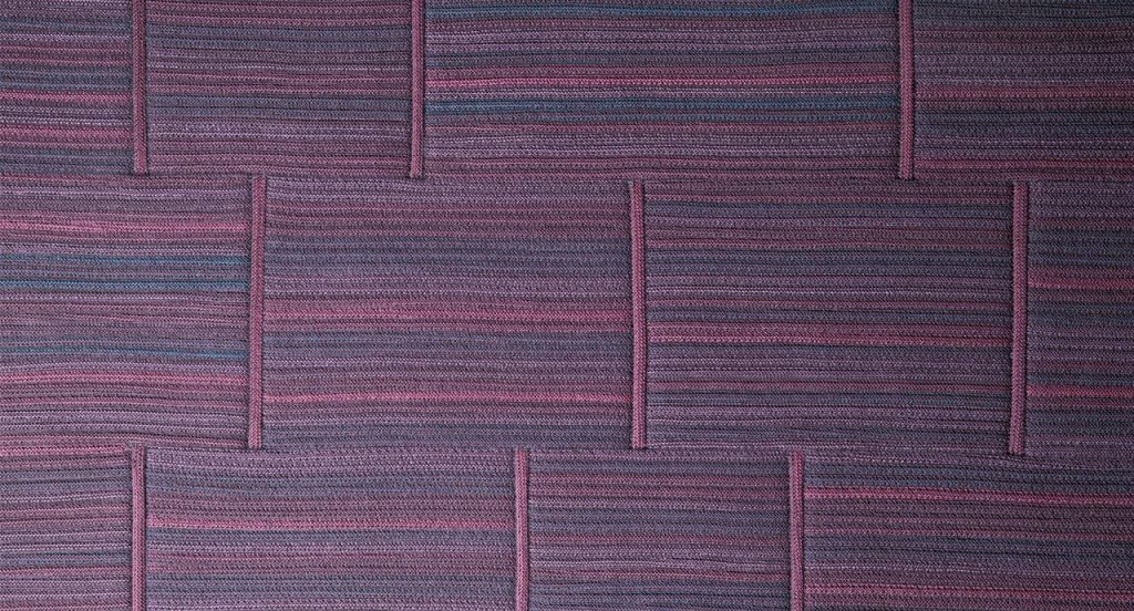 Incroci rug by joining stripes sawn lengthwise made of purple wool cords.
