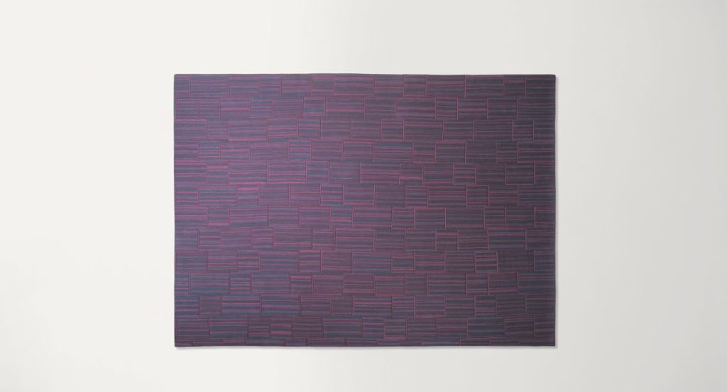Incroci rug by joining stripes sawn lengthwise made of purple wool cords on a white background.