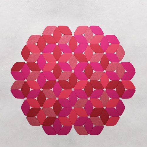 Kaleidoscope rug made of pink and red felt modules on a grey background.