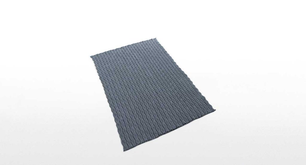 Marea rug, made of braids shaped like waves in grey Rope yarn on a white background.