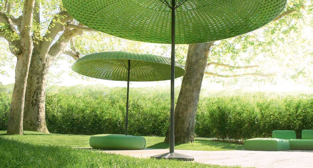 Two Mogambo parasols, structure in black aluminium and steel, top of green rope yarn in a garden.
