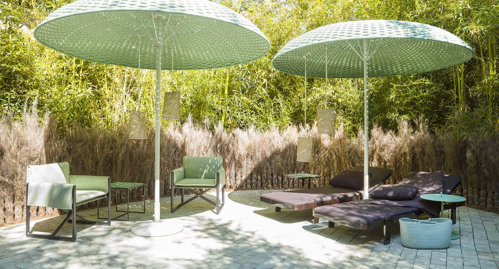 Two Mogambo parasols, structure in white aluminium and steel, top of green rope yarn in a garden.