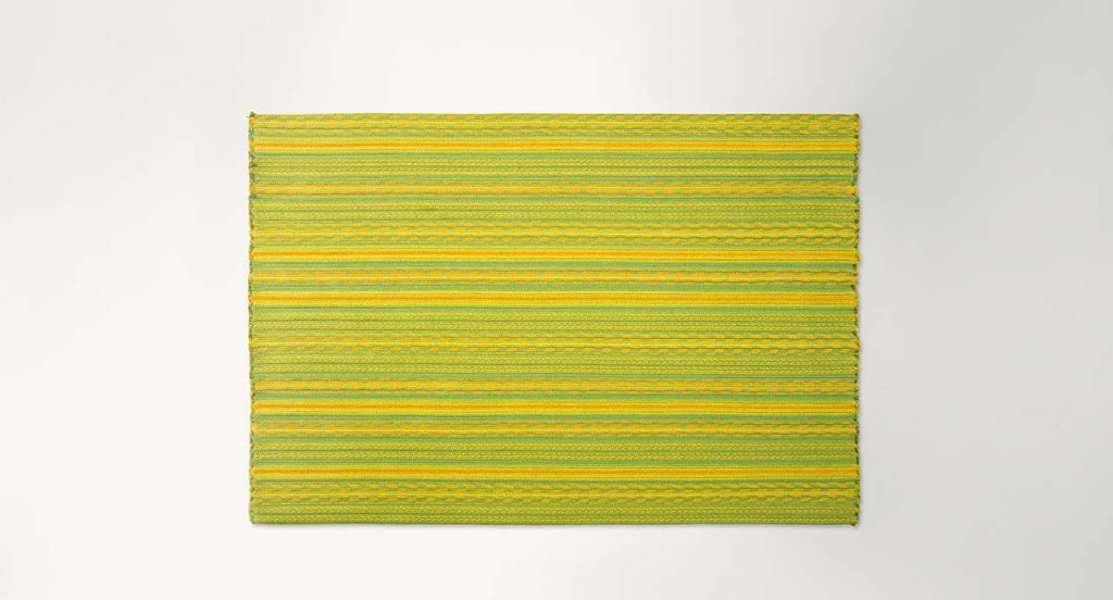 Navajo rug made of green and yellow rope braids on a white background.