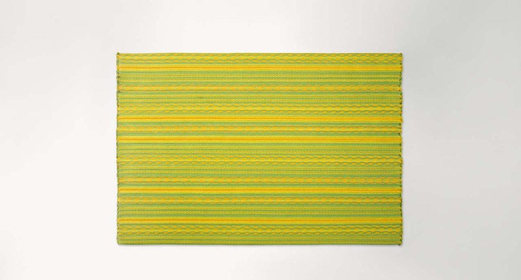 Navajo rug made of green and yellow rope braids on a white background.
