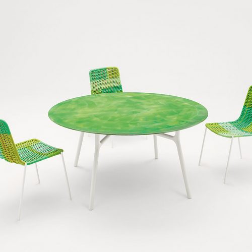 Nesso Outdoor Dining Table, four legs ins white aluminium. top in green water like pattern in a living room.
