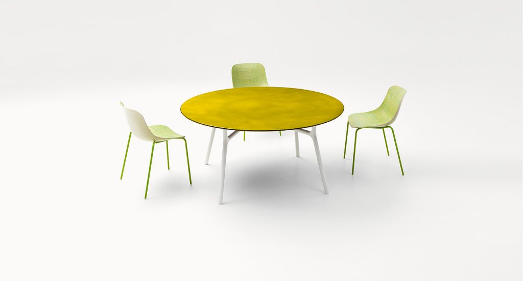 Nesso Outdoor Dining Table, four legs in white aluminium. top in yellow water like pattern in a living room.