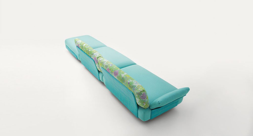 Three blue Oasi, Series of single seatings, two with backrest and one of them with armrest in green and pink garden like patttern on a white background.