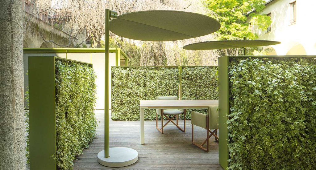 Two green Ombra sunshades top made of two polyester semi circles, leg in aluminum in a terrace.