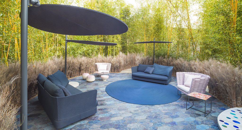 Three blue Ombra sunshades top made of two polyester semi circles, leg in aluminum in a garden.