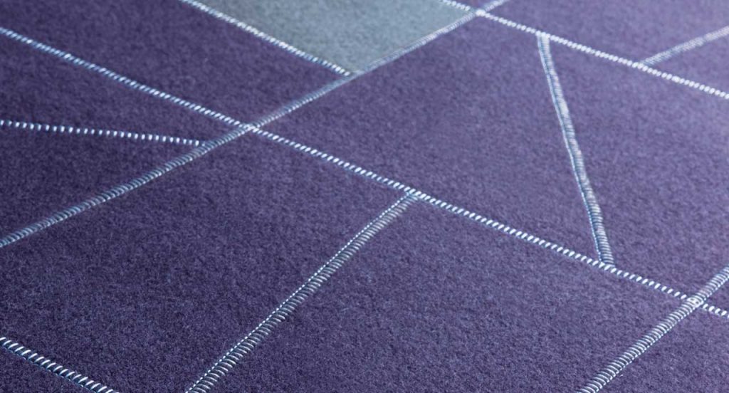 Origami rug made of felt, squares and diagonal stitching in purple and grey colors.