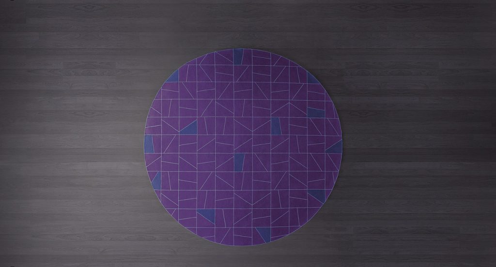 Round Origami rug made of felt, squares and diagonal stitching in purple and grey colors on a brown floor.