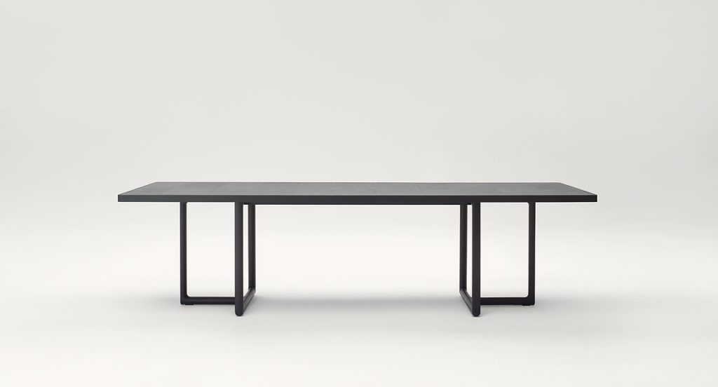 Large Portofino Outdoor Dining Table, two legs in dark heartwood, top in natural lava stone on a white background.