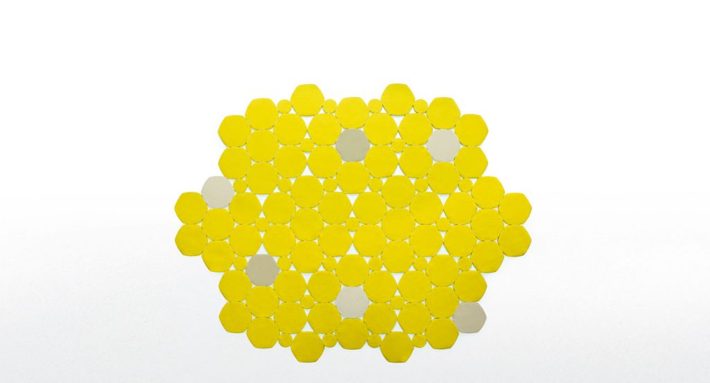 Prisma rug made by hexagonal, irregular forms in yellow and beige felt on a white background.
