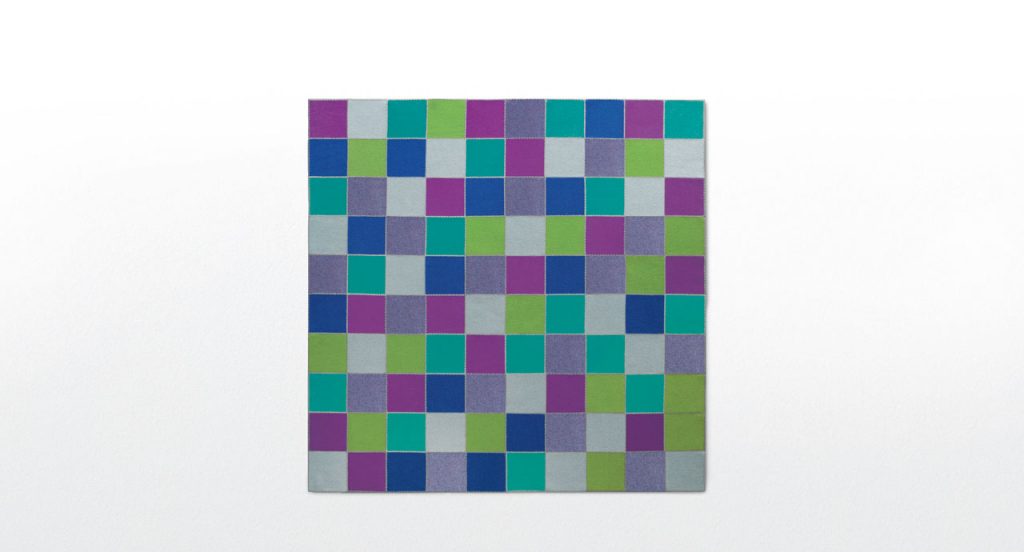 Quadri rug made with grey, blue, puple and green felt squares on a white background.