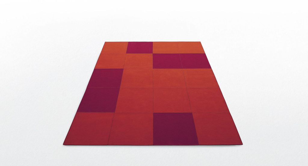 Quadri rug made with red and purple felt squares on a white background.