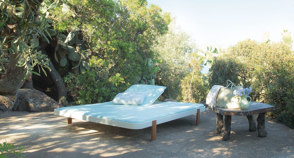 Double Rams sun bed with backrest, four legs in brown wood, cover in white polyester in a terrace.