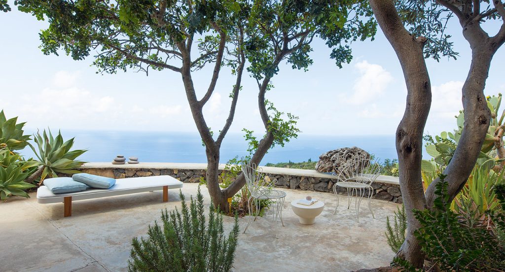 Single Rams sun bed with backrest, four legs in brown wood, cover in white polyester in a terrace.