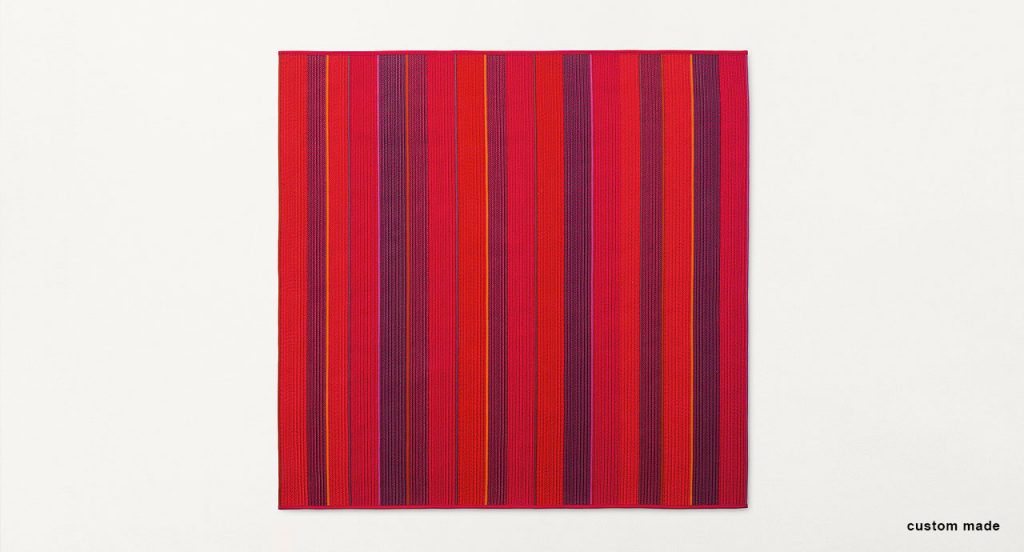 Ray rug made with red and purple wide braids on a white background.