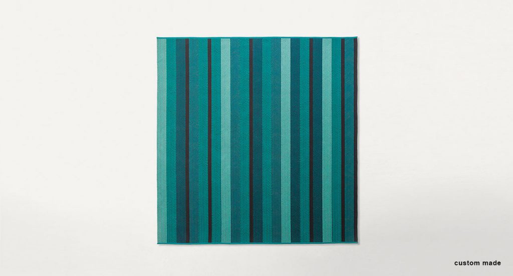 Ray rug made with blue and black wide braids on a white background.