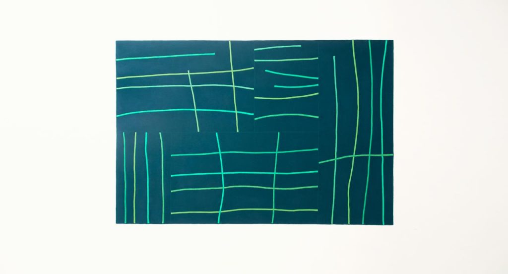 Blue and green Rilievo rug in wool cords and lines like pattern on a white background.