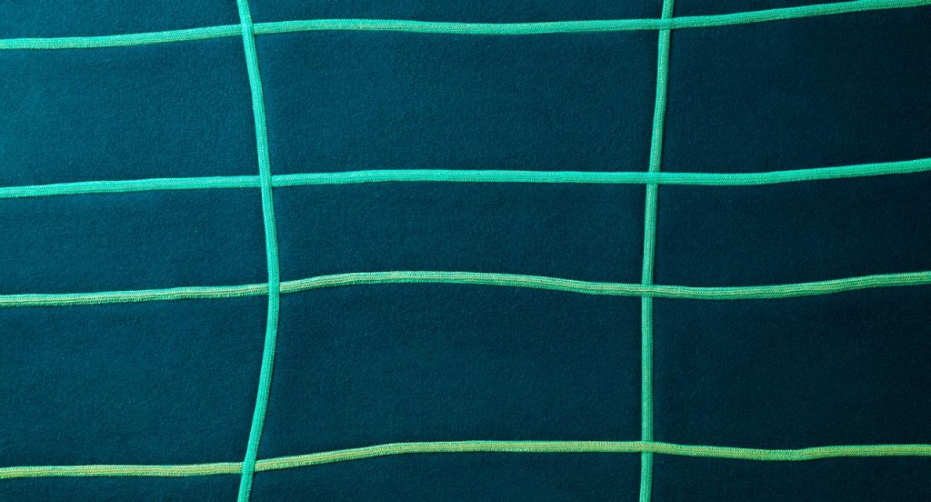 Blue and green Rilievo rug in wool cords and lines like pattern.