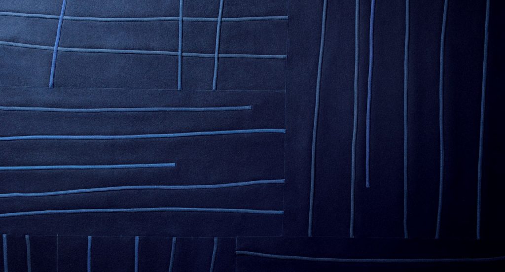 Blue Rilievo rug in wool cords and lines like pattern.