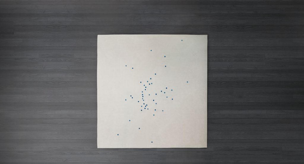 White Rosae rug, round reised pattern in grey, blue and yellow wool on a grey background.