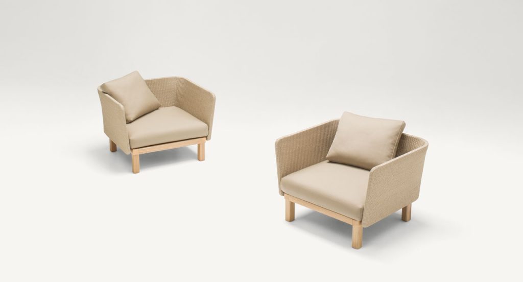 Two beige Sabi Armchairs, base and two legs made of natural wood, backrest in woven rope cord and cushion in fabric on a white background.