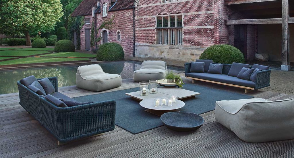 Two Sabi Sectionals, base and two legs in natural wood, upholstery in blue fabric in a terrace.