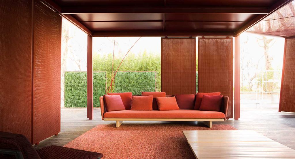 Sabi Sectional, base and two legs in natural wood, upholstery in red fabric in a living room.