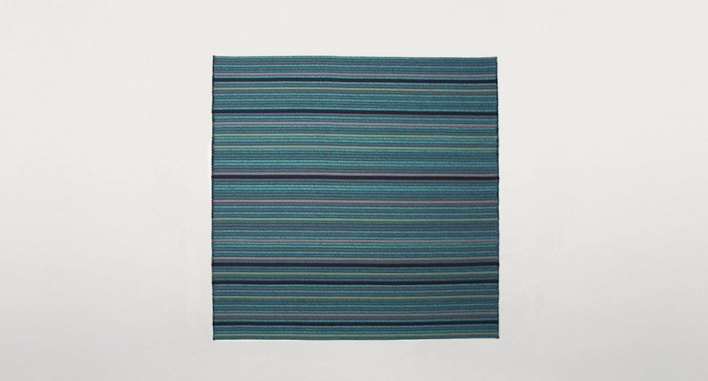 Samo rug made of grey, black and blue rope cords and irregular shape on a white background.