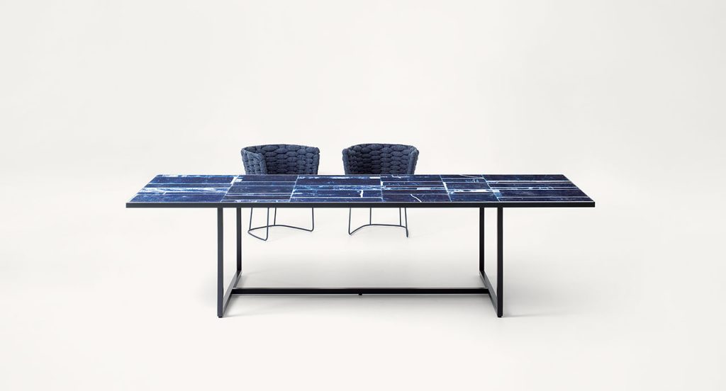 Blue Sciara Dining Table, structure and two legs in black steel, top in lava stone in a dining room.