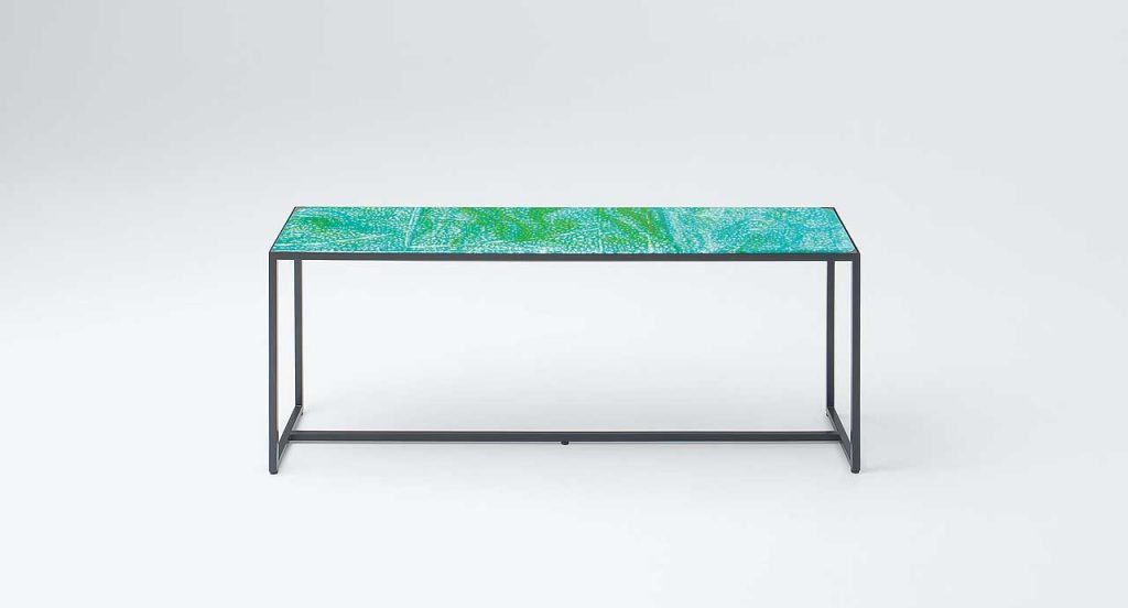 Blue and green Sciara Dining Table, structure and two legs in black steel, top in lava stone on a white background.